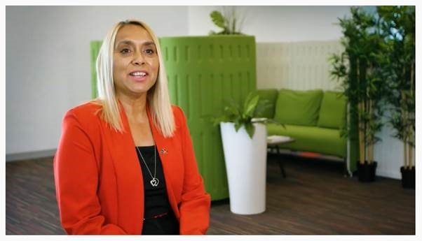 Director for Aboriginal Health sitting in meeting room wearing an orange blazer with a lime green sofa in the background.