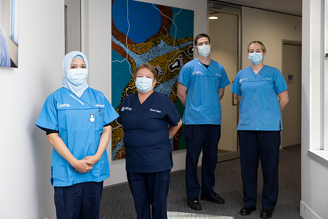 Four nursewest nurses, wearing masks standing together in a hallway