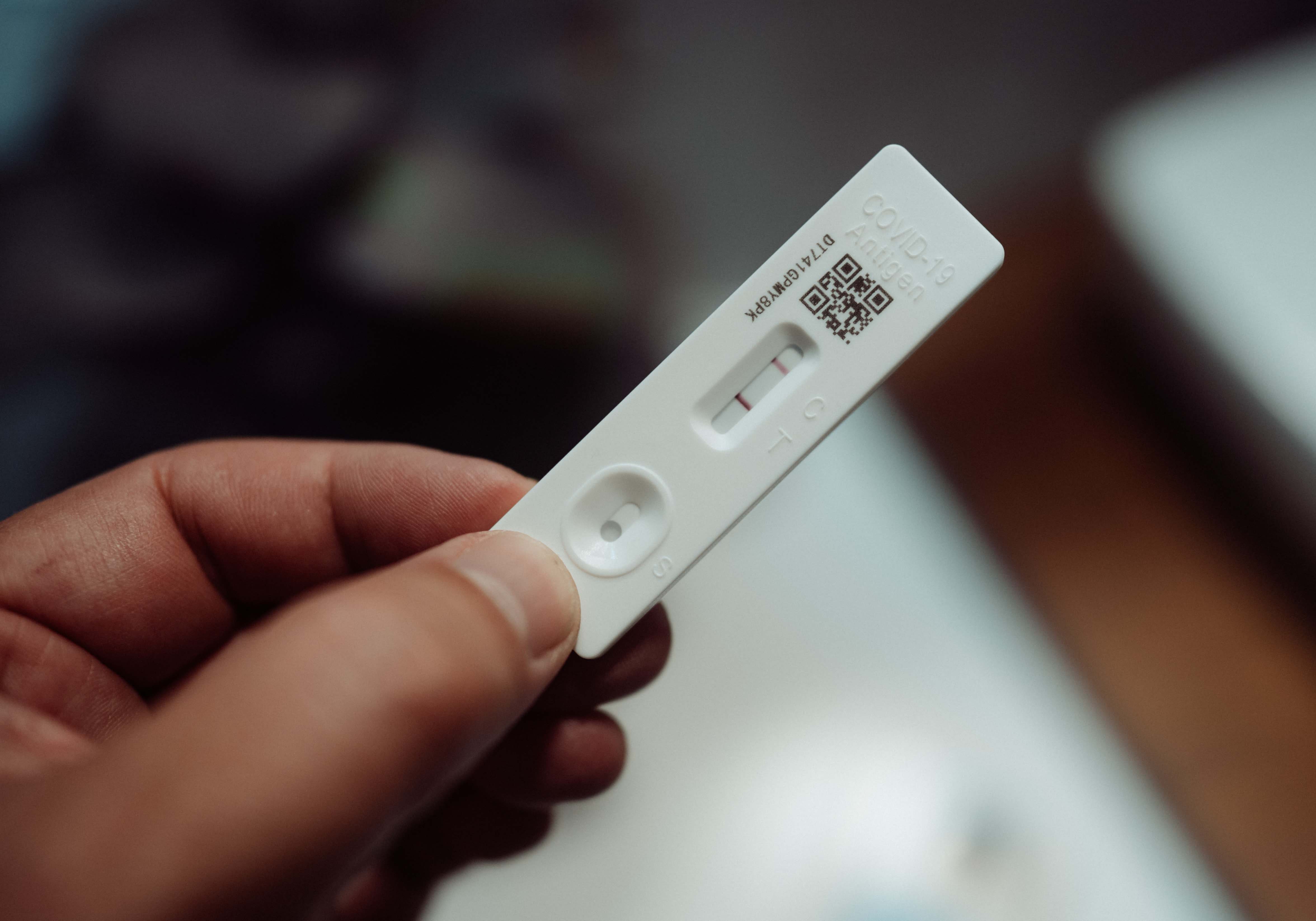 hand holding positive RAT test