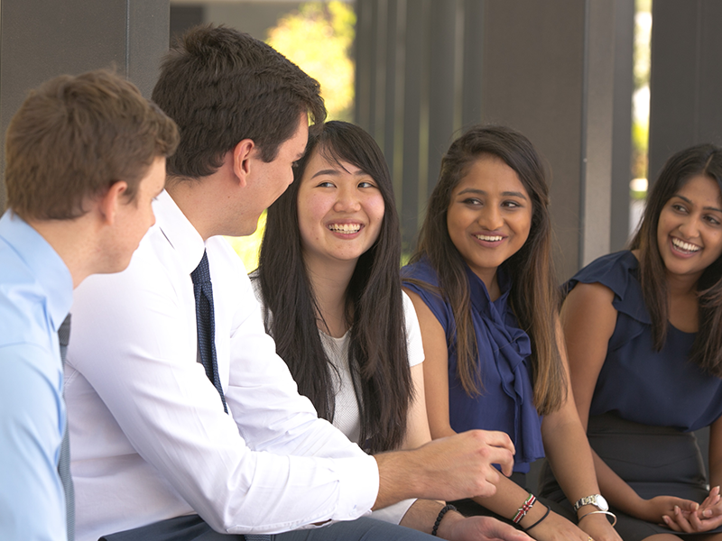 group of people sitting in a line talking and smiling