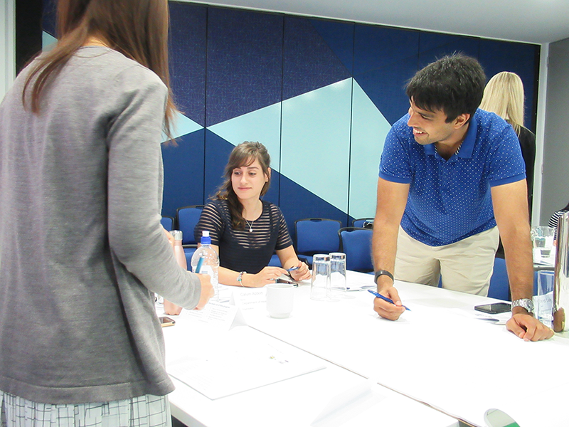 Men and women talking and smiling around a work table