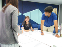 Men and women talking and smiling around a work table