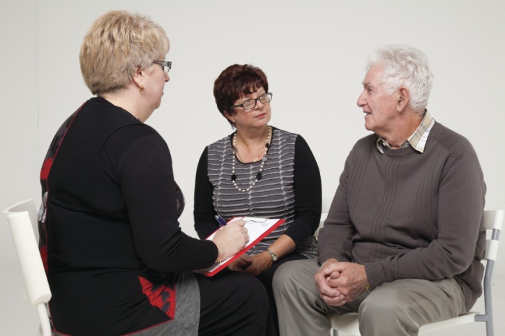 woman with clipboard talking to a man and woman 