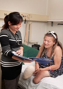 Health professional showing notes to a woman, who has had both legs amputated