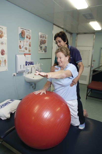 Female health professional assisting older patient with arms exercises