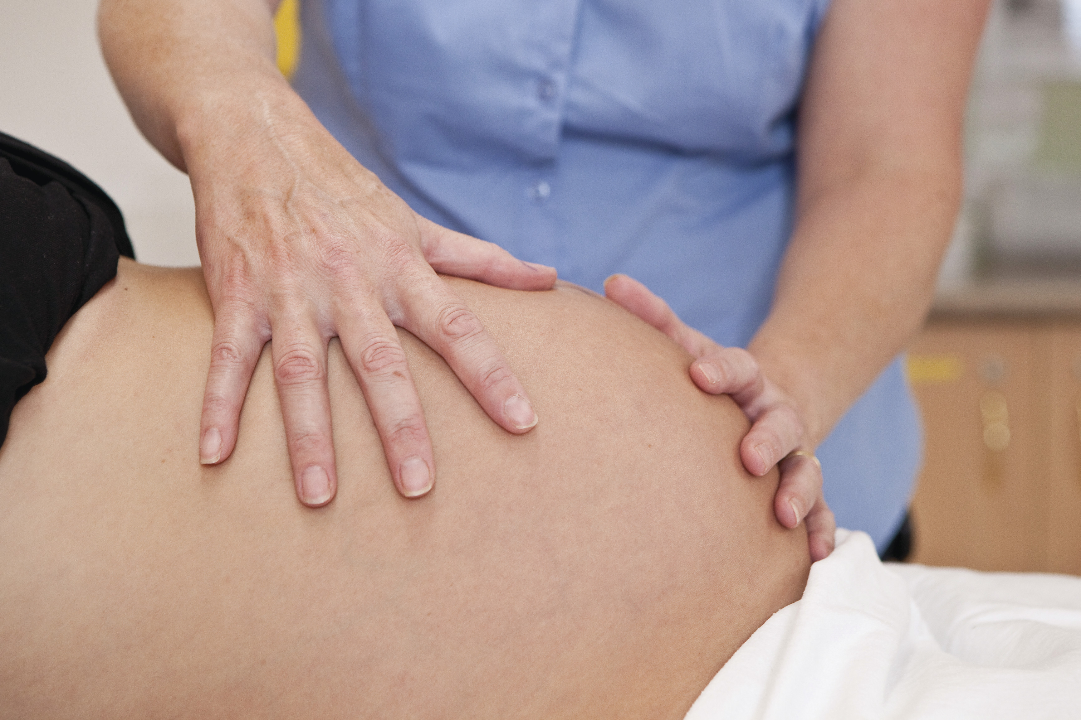 Midwife palpating abdomen of pregnant woman