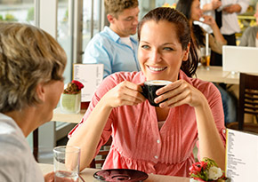 Woman in her 30s drinking coffee with her mum at a coffee shop