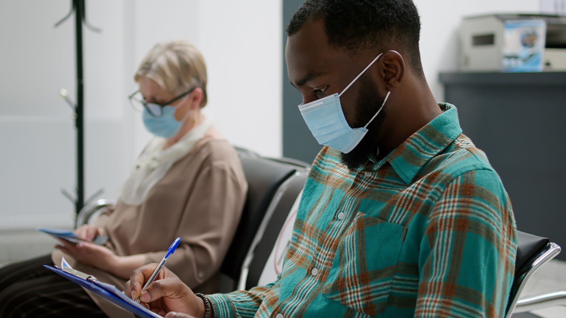 Two people in waiting room wearing surgical masks