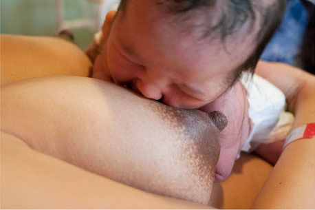 the baby is nuzzling its face towards the nipple