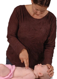 Woman placing two fingers on an infant’s chest and pushing down to perform chest compressions.