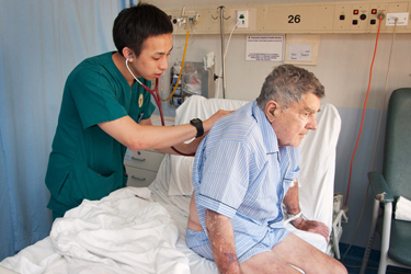 Health care professional with stethoscope placed on patient's back