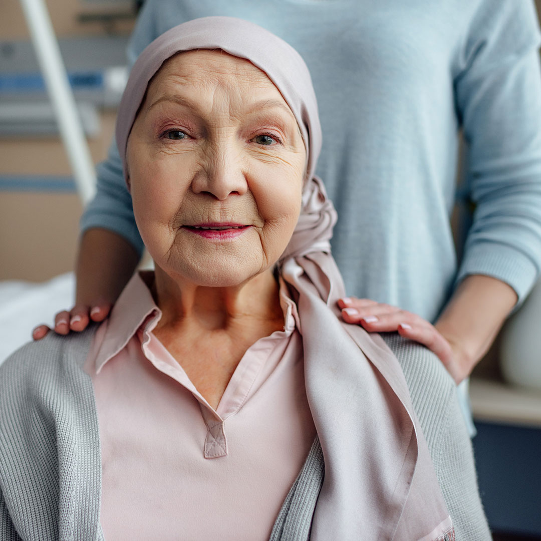Elderly hospital patient sitting with daughters hands on her shoulders